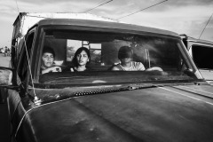 A family sits in a truck at Paraguachón, Colombia's border town, heading to the central city of Maicao on August 11, 2018. There, smuggling, theft, extortion, violence, and human trafficking are normalized practices. Those who can afford a bus ticket move to bigger cities of the Northern Colombian coast, such as Barranquilla, Cartagena, or to the capital city Bogotà. Others continue the journey on foot. Many end up living in the streets or informal camps on the outskirt of the town, with no guarantee of food, clean water, and health care. 
Early in 2020, the Colombian government announced two new Special Stay Permits that would allow more than 100,000 Venezuelans to stay and work in the country, and ruled that children born in the country to Venezuelan parents could acquire Colombian nationality, but vast numbers of people remain dispossessed.