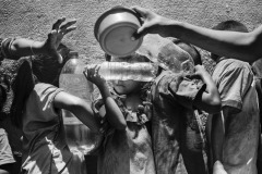 Venezuelan children hold plastic bottles filled with water while they wait in line for a free meal at a charity organization in Paraguachón, Colombia, on August 10, 2019. According to UNICEF, out of the 1.8 million Venezuelans settled in Colombia, 430 thousand are children and adolescents. Migrant children are trapped in a dangerous environment and, without access to education, they are born and grow with no horizon of comparison for their condition. As the unstable environment doesn't change, the children and the adolescents seem to have learned to live with a constant feeling of danger and exacerbated alertness. Families from neighboring Venezuela walk into Colombia to eat, fill bottles with potable water, and return home. Often, they are indigenous Wayuu, of Venezuelan nationality.