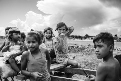 Venezuelan children sit in a cart in an informal settlement known as La Pista, located around an abandoned airport on the Maicao's outskirts in La Guajira, Colombia, on September 28, 2020.
In migrant settlements, people do not have running water or sanitation access. Health care has become a particular concern during the pandemic, as access to hospitals was limited to emergencies. People rely on medical brigades of international organizations that have no means for specific interventions other than treating generic ailments.
In 2020, the photographer worked in the area with the collaboration of leaders of the migrant community who assisted with the work and ensuring the families' consent to photograph. By the end of that year, the photographer ideated a project to promote self-representation and journalism for the community's children, women, and men. The United Nations Refugee Agency (UNHCR) offered funding to buy photo cameras and implement the project in a temporary center where people are provided food and housing for a month upon their arrival.